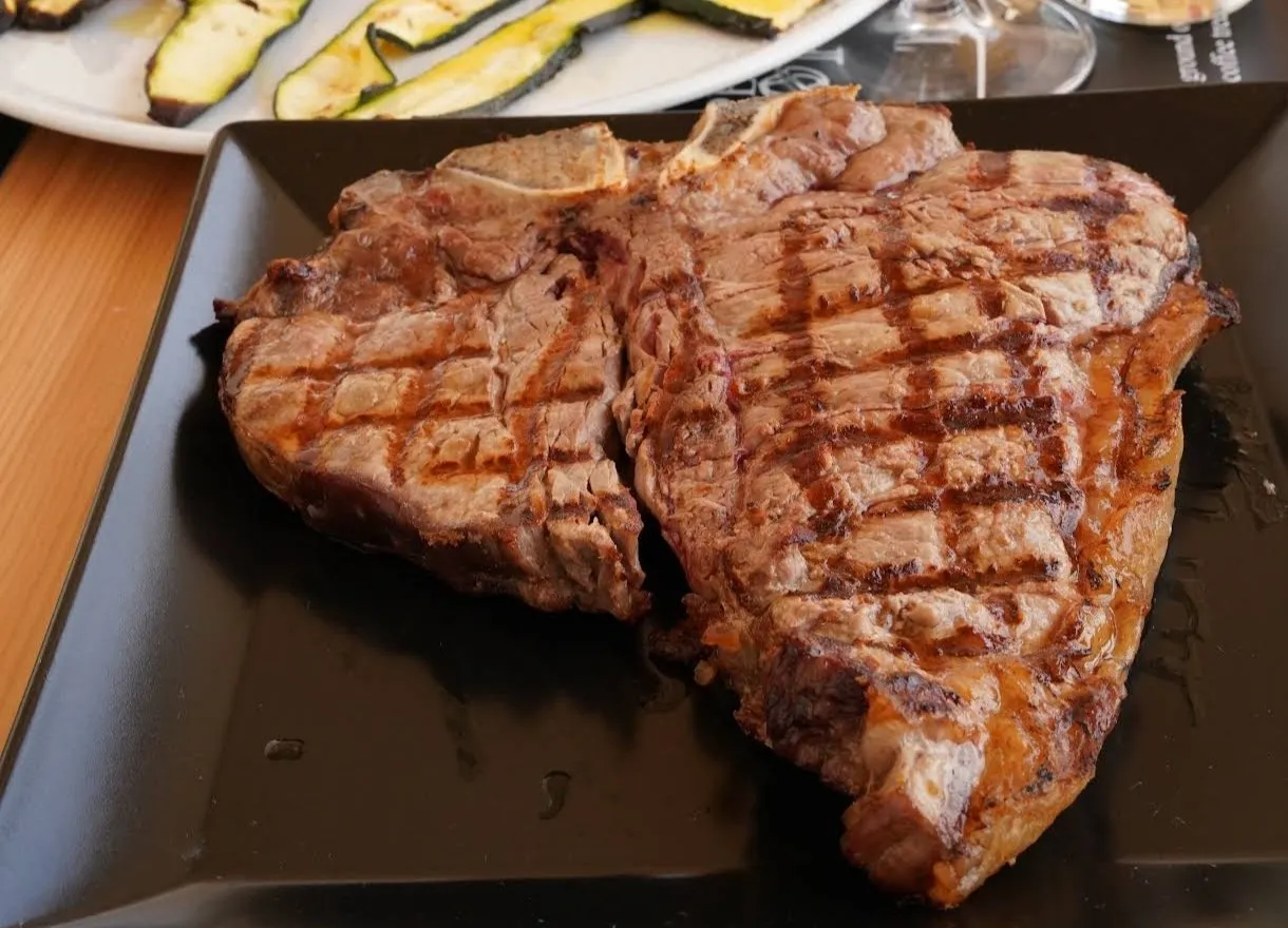 Bistecca alla griglia tagliata a fette, servita su tagliere nero, in un tavolo del ristorante Il Tagliere Ragusa