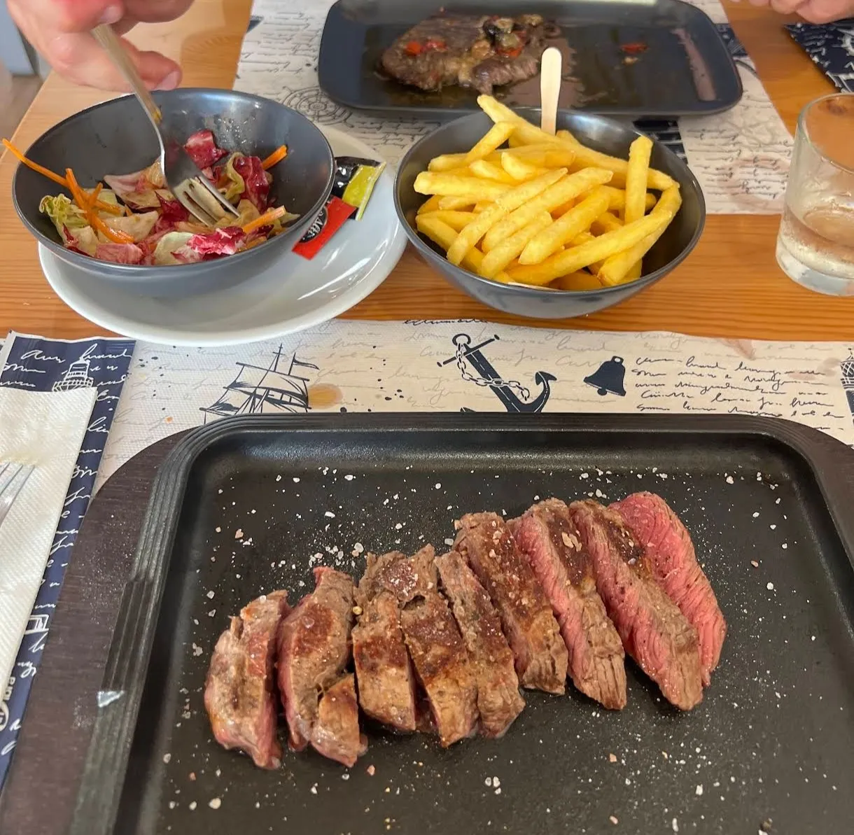 Bistecca alla griglia servita con patatine fritte e insalata